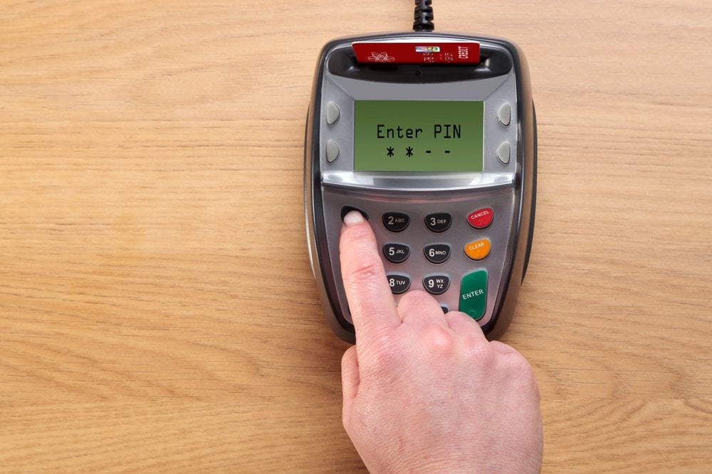 Photo of a woman entering a PIN number with a Debit Card