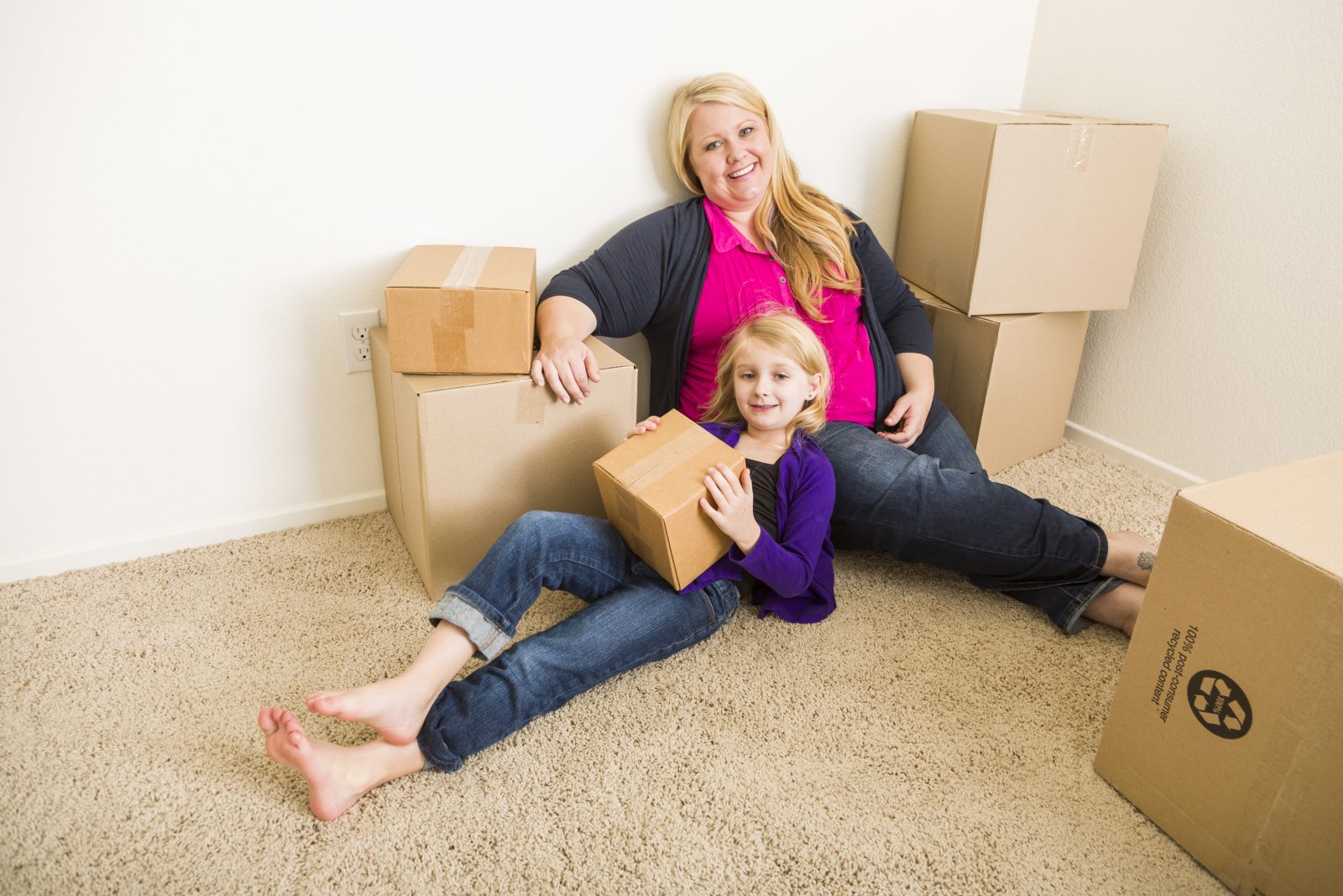 A single mom and her daughter unpack boxes in their new house.