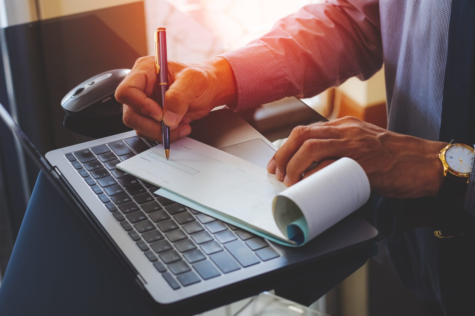 Individual writing a check and is vulnerable to check fraud.