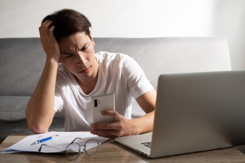 Worried college student staring at his phone intensely.