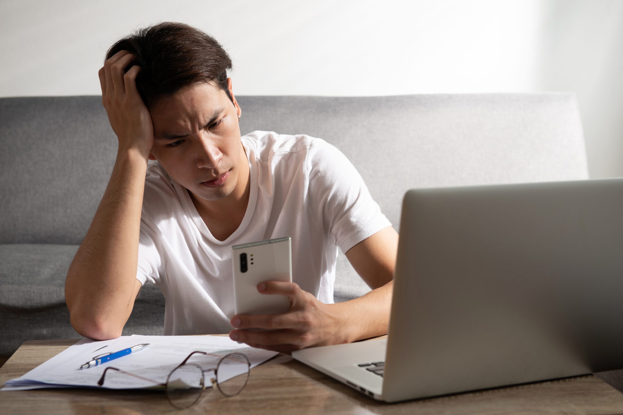 Worried college student staring at his phone intensely.