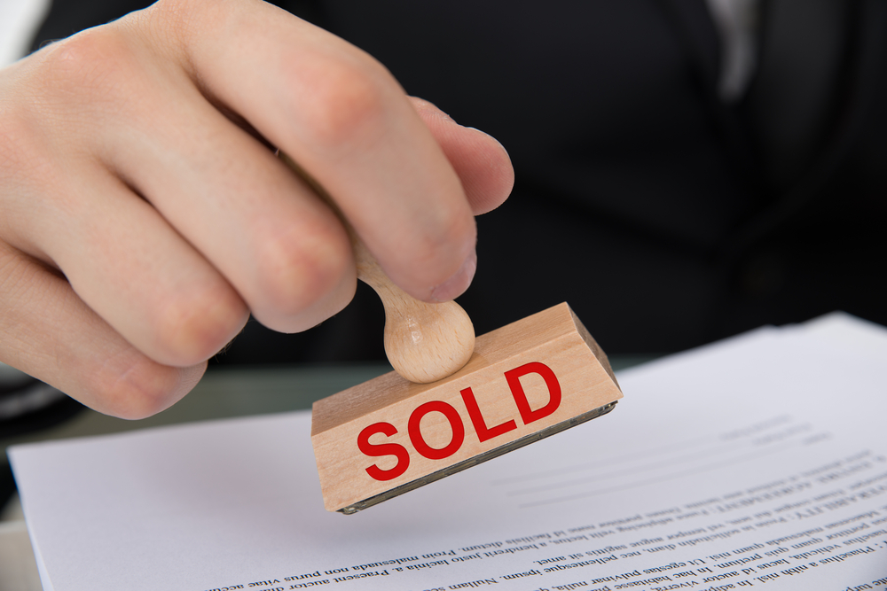 Contract documents with a "sold" stamp , completing a medical practice buy-in or buy-out.